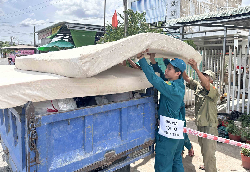 Lực lượng chức năng hỗ trợ các hộ dân bị sạt lở nhà di dời tài sản. (Ảnh: Thanh Liêm/TTXVN)