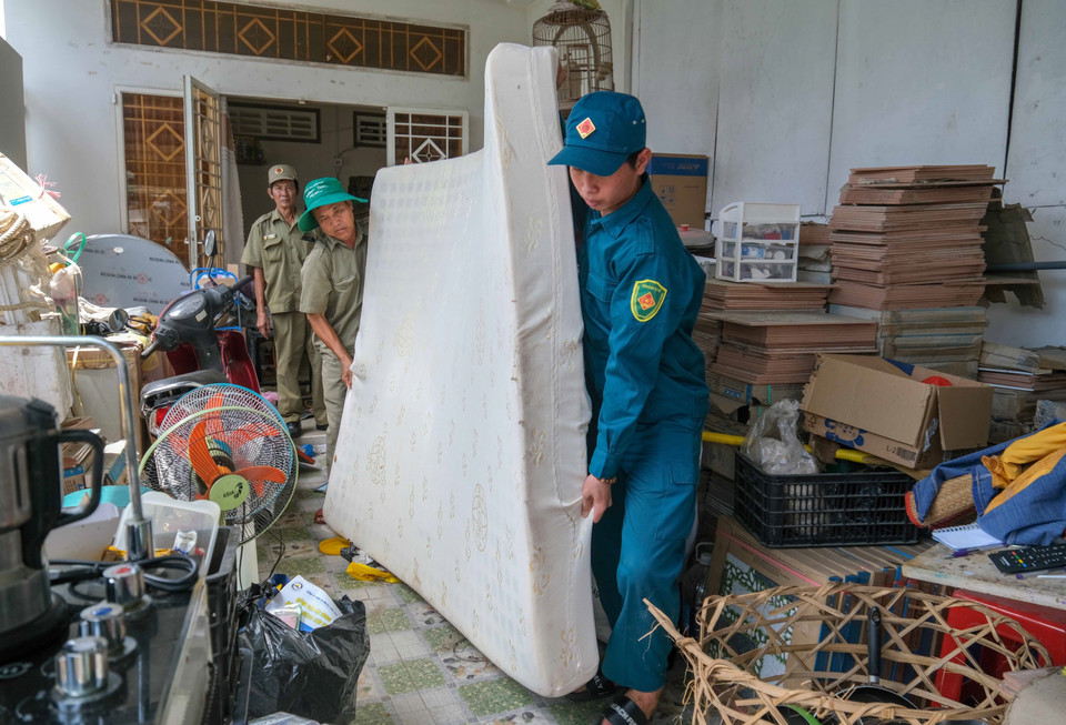 Lực lượng chức năng hỗ trợ các hộ dân bị sạt lở nhà di dời tài sản. (Ảnh: Thanh Liêm/ TTXVN)