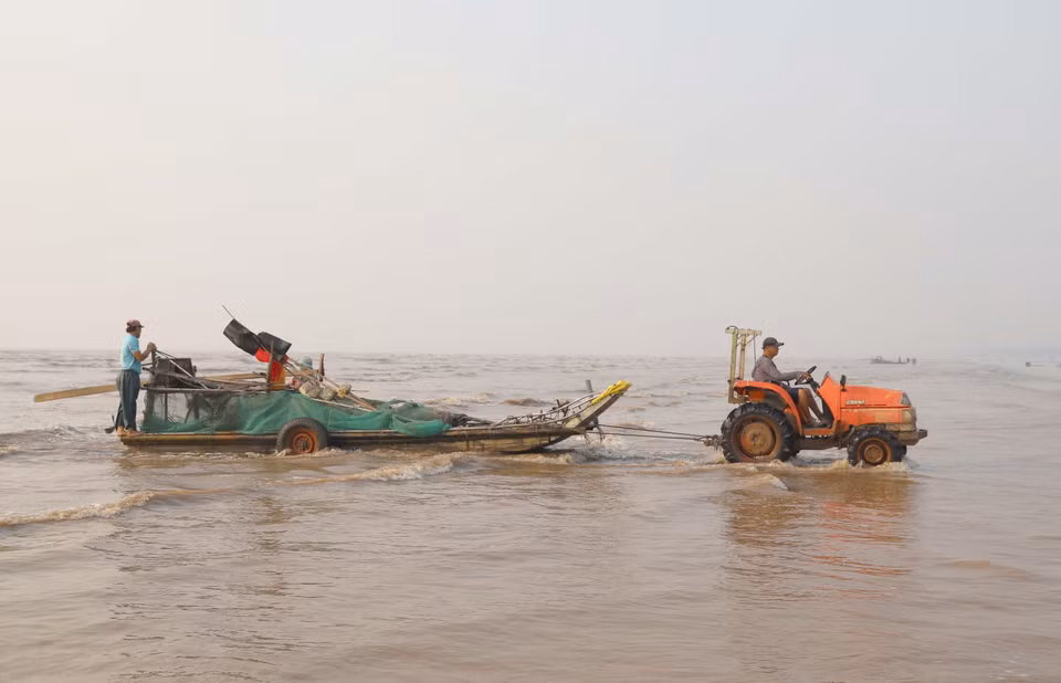 Dùng máy kéo và hệ thống bánh xe nâng để kéo bè mảng vừa cập bờ lên bãi đậu. (Ảnh: Xuân Tiến/TTXVN)