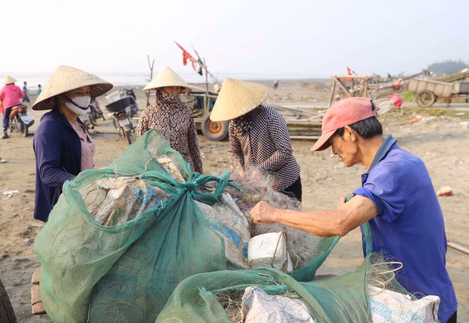 Ngư dân và tiểu thương chuẩn bị gỡ hải sản ra khỏi lưới. (Ảnh: Xuân Tiến/TTXVN)