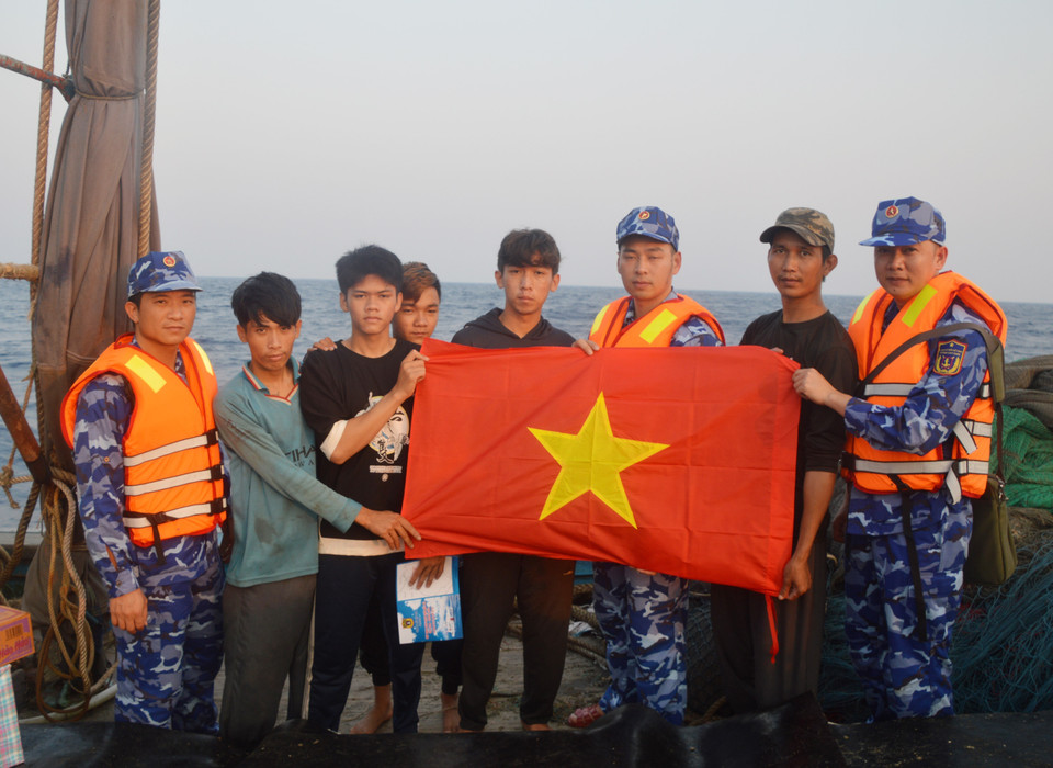 Lực lượng Cảnh sát Biển tặng cờ Tổ quốc cho ngư dân. (Ảnh: Mạnh Thường/TTXVN)