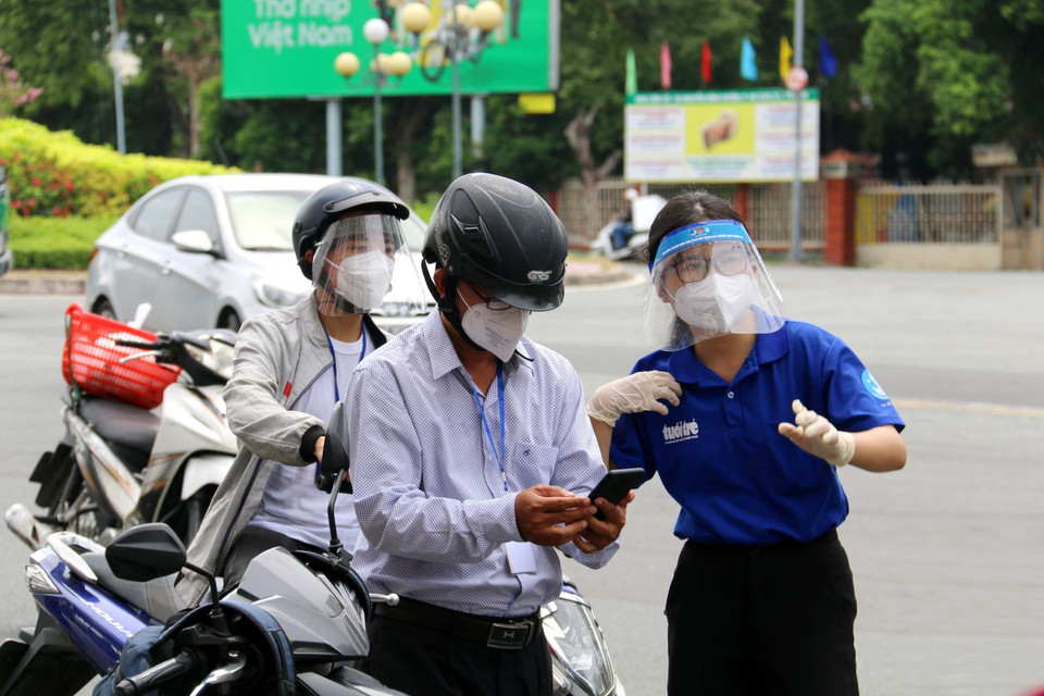 Lực lượng chức năng hỗ trợ người dân thực hiện khai báo thông di biến động trên đường Điện Biên Phủ, quận Bình Thạnh, Thành phố Hồ Chí Minh. (Ảnh: Thanh Vũ/TTXVN)