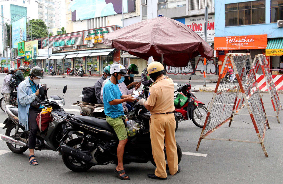 Trong trường hợp người dân không có điện thoại thông minh để khai báo, cán bộ tại chốt sẽ phát phiếu khai báo y tế cho người dân để khai. (Ảnh: Thành Chung/TTXVN)
