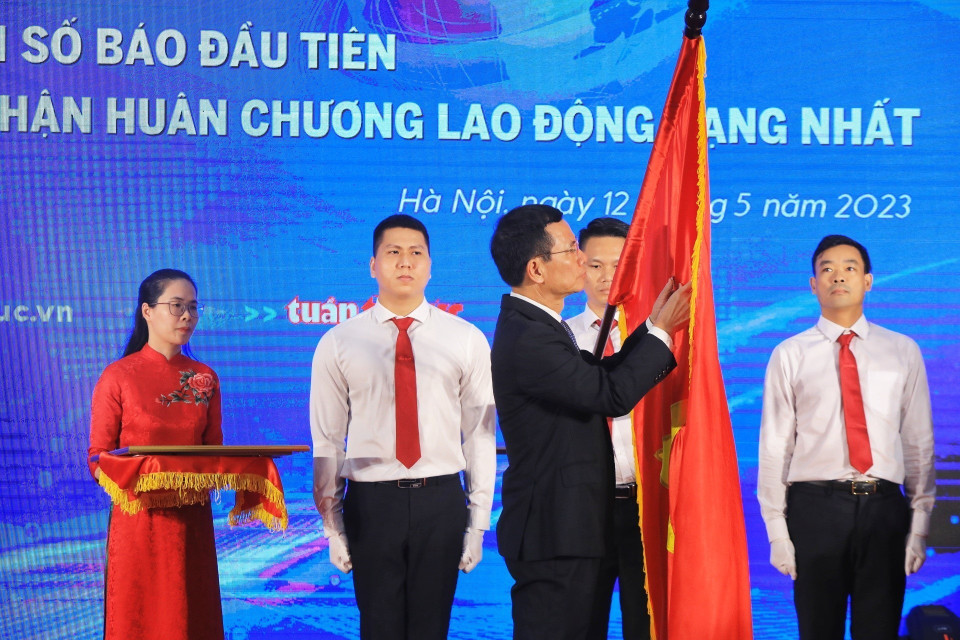 Bộ trưởng Bộ Thông tin và Truyền thông Nguyễn Mạnh Hùng gắn Huân chương Lao động hạng Nhất lên lá cờ truyền thống của Báo Tin tức. (Ảnh: Tuấn Anh/TTXVN)