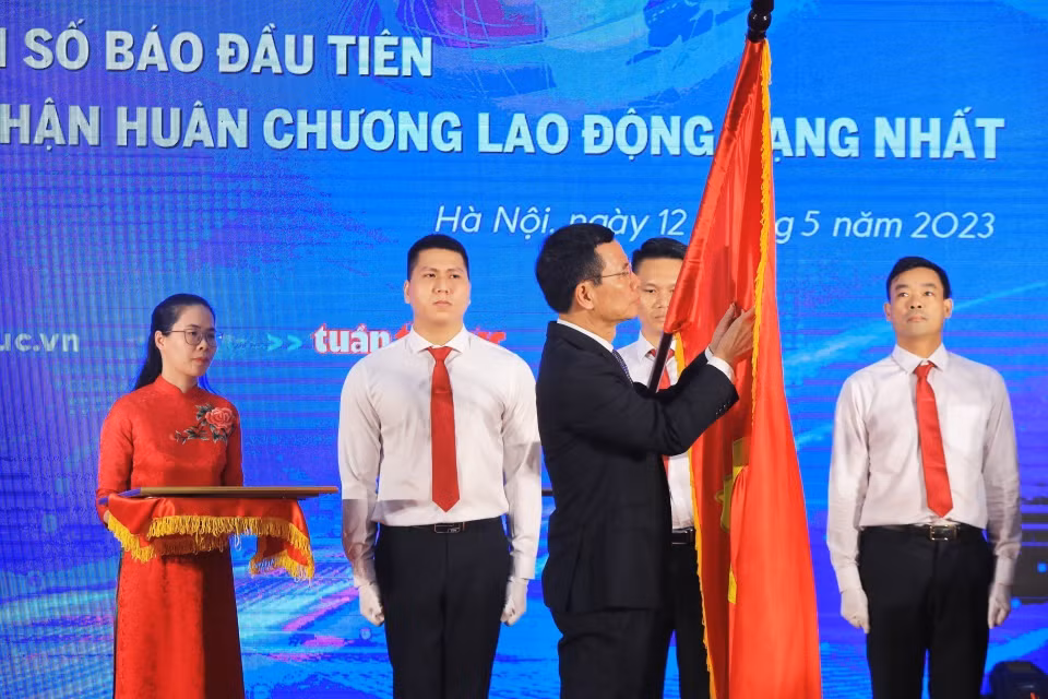 Bộ trưởng Bộ Thông tin và Truyền thông Nguyễn Mạnh Hùng gắn Huân chương Lao động hạng Nhất lên lá cờ truyền thống của Báo Tin tức. (Ảnh: Tuấn Anh/TTXVN)
