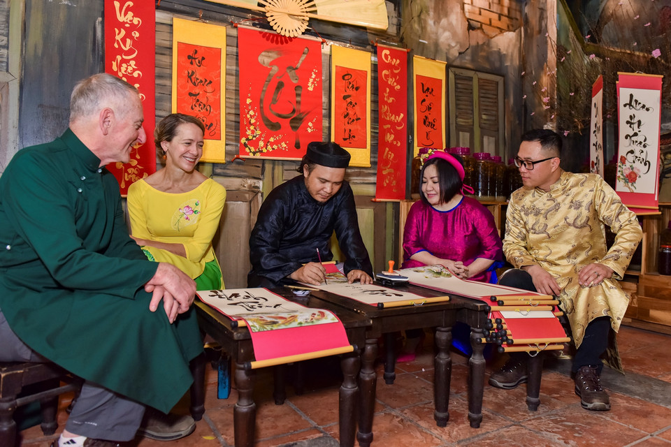 Tất cả các khách mời quốc tế đến tham dự đều diện áo dài truyền thống, cùng nhau trải nghiệm văn hóa, phong tục truyền thống Việt Nam như viết thư pháp, làm tò he, hát quan họ…(Ảnh: CTV/Vietnam+)