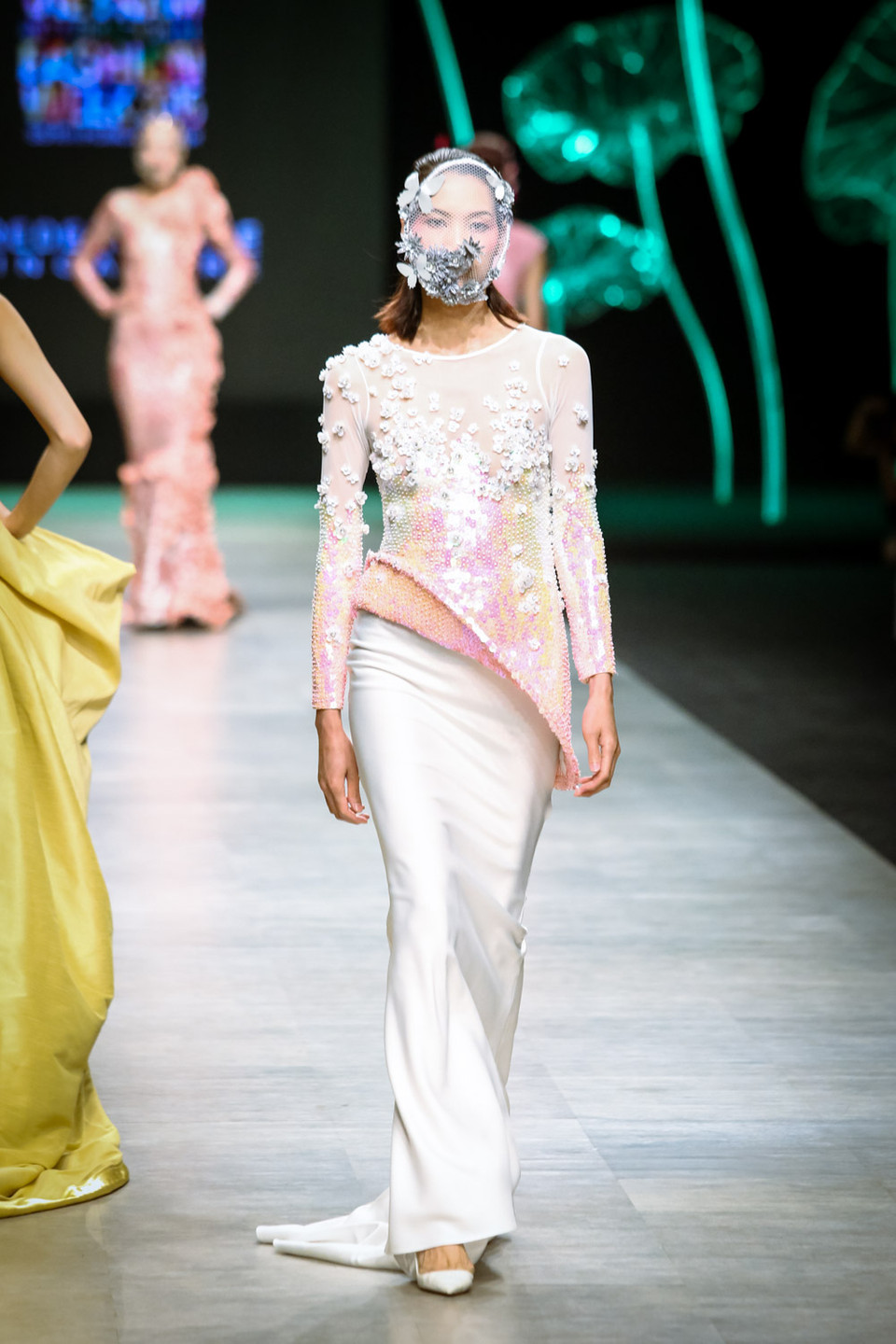 Gam màu chủ đạo của bộ sưu tập là sự chuyển động giữa các sắc màu từ trắng ánh bạc, hồng phấn thanh lịch đến gam màu tím đậm, xanh ngọc bảo sâu thẳm.