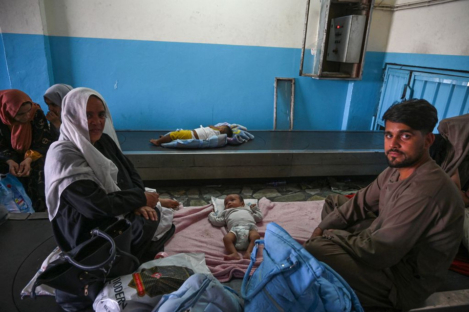 Một gia đình ngồi chờ trên băng chuyền hành lý ở sân bay Kabul.(Nguồn: AFP)