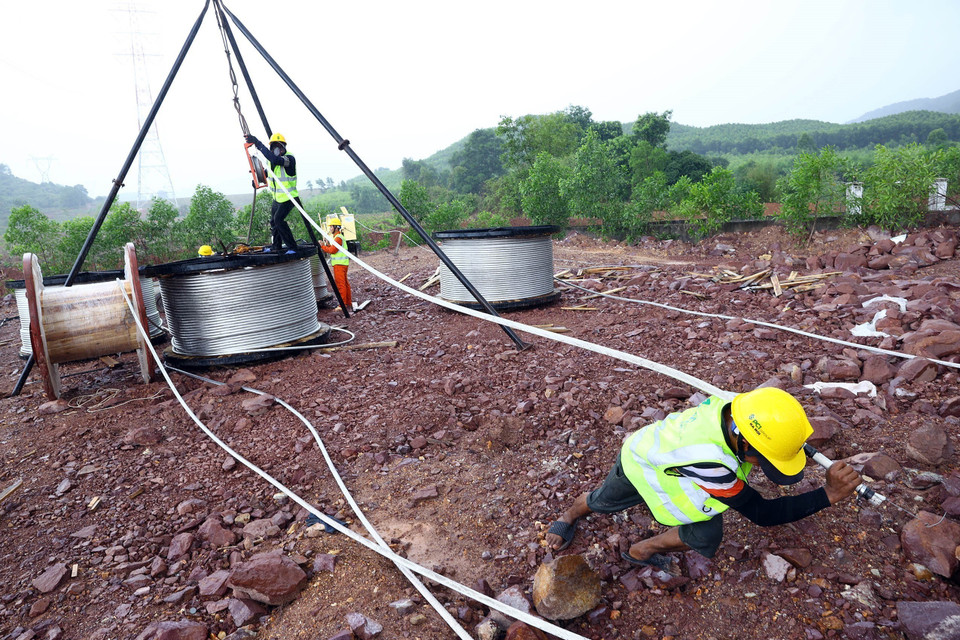 Công nhân PC1 thi công kéo dây trong mưa tại khoảng néo 134-137 trên địa bàn huyện Cẩm Xuyên (Hà Tĩnh) đoạn Quảng Trạch-Quỳnh Lưu. (Ảnh: Huy Hùng/TTXVN)