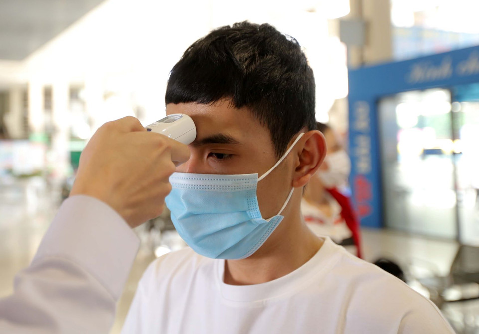 Hành khách được xịt sát khuẩn và đo thân nhiệt trước khi vào bến. (Ảnh: Hoàng Hiếu/TTXVN)