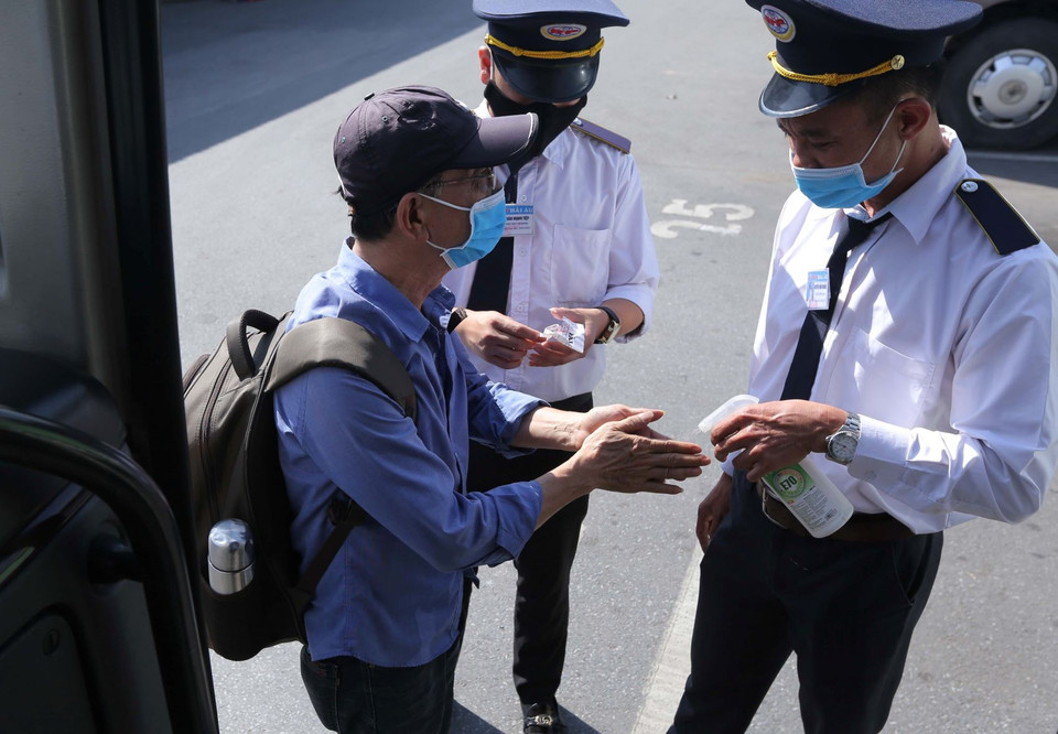 Xịt sát khuẩn tay cho hành khách trước khi lên xe. (Ảnh: Hoàng Hiếu/TTXVN)