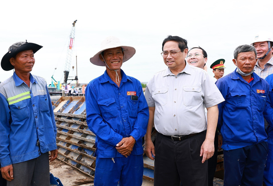 Thủ tướng Phạm Minh Chính với công nhân thi công Dự án Cao tốc Châu Đốc-Cần Thơ-Sóc Trăng. (Ảnh: Dương Giang/TTXVN)