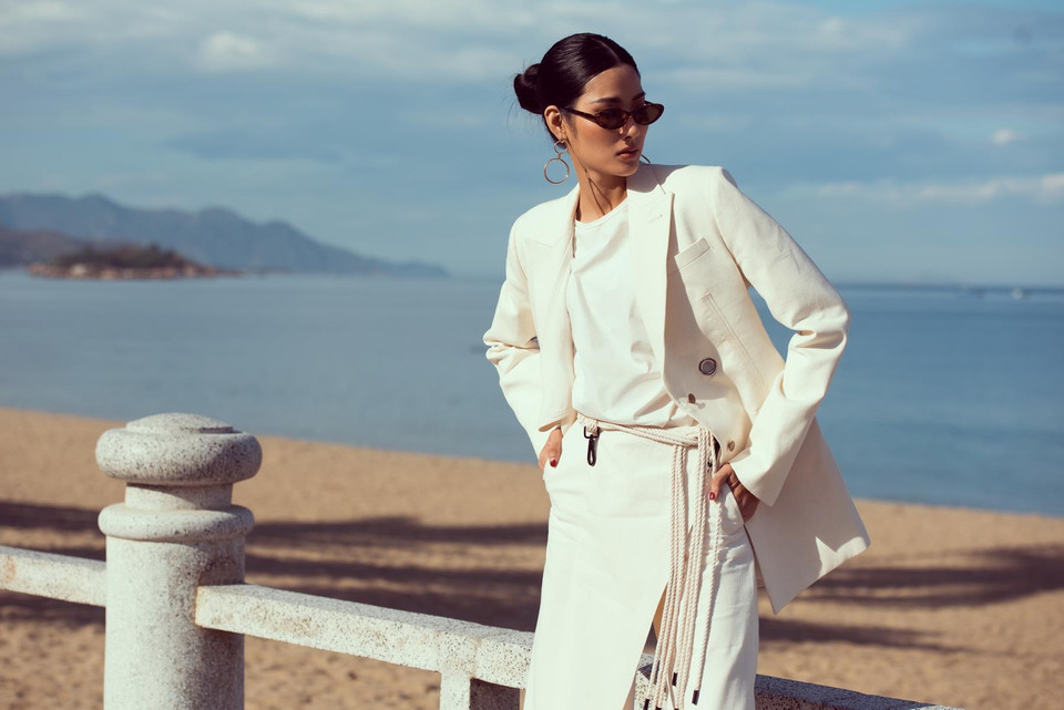 Trong bộ ảnh thực hiện ở bãi biển, Á hậu Hoàng Thùy chọn sắc trắng với trang phục của Lâm Gia Khang kết hợp cùng mắt kính đen, tôn gương mặt góc cạnh và làn da nâu khỏe mạnh. (Ảnh: Quang Đức/Vietnam+)