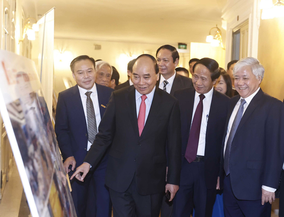 Chủ tịch nước Nguyễn Xuân Phúc và các đại biểu xem trưng bày ảnh tại buổi lễ. (Ảnh: Thống Nhất/TTXVN)