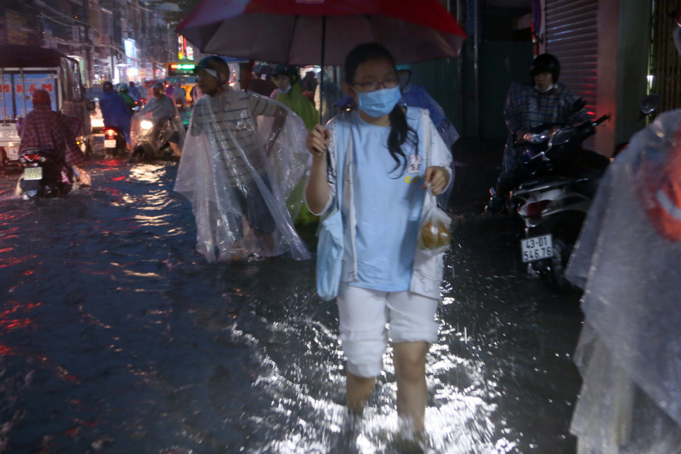 Người dân lội nước đi mua đồ ăn trên đường Hùng Vương. (Ảnh: Trần Lê Lâm/TTXVN)