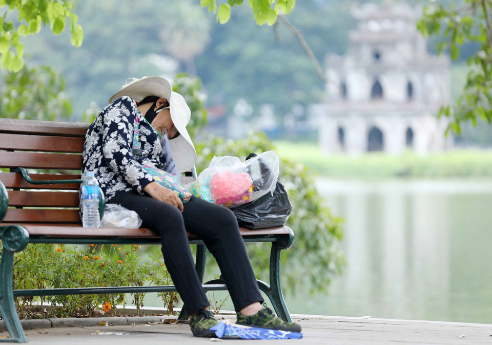 Một người bán hàng mệt mỏi trong thời tiết nắng nóng trưa 28/6/2022. (Ảnh: Hoàng Hiếu/TTXVN)