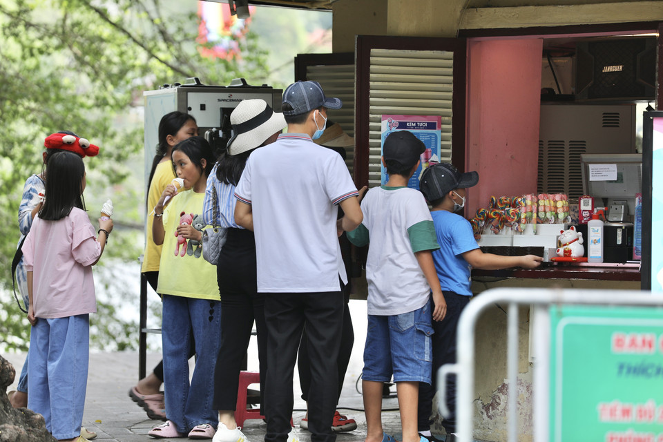 Nhiều người dân lựa chọn ăn kem, uống nước tại các cửa hàng giải khát khu vực Hồ Gươm để giải nhiệt trong ngày nắng nóng. (Ảnh: Hoàng Hiếu/TTXVN)
