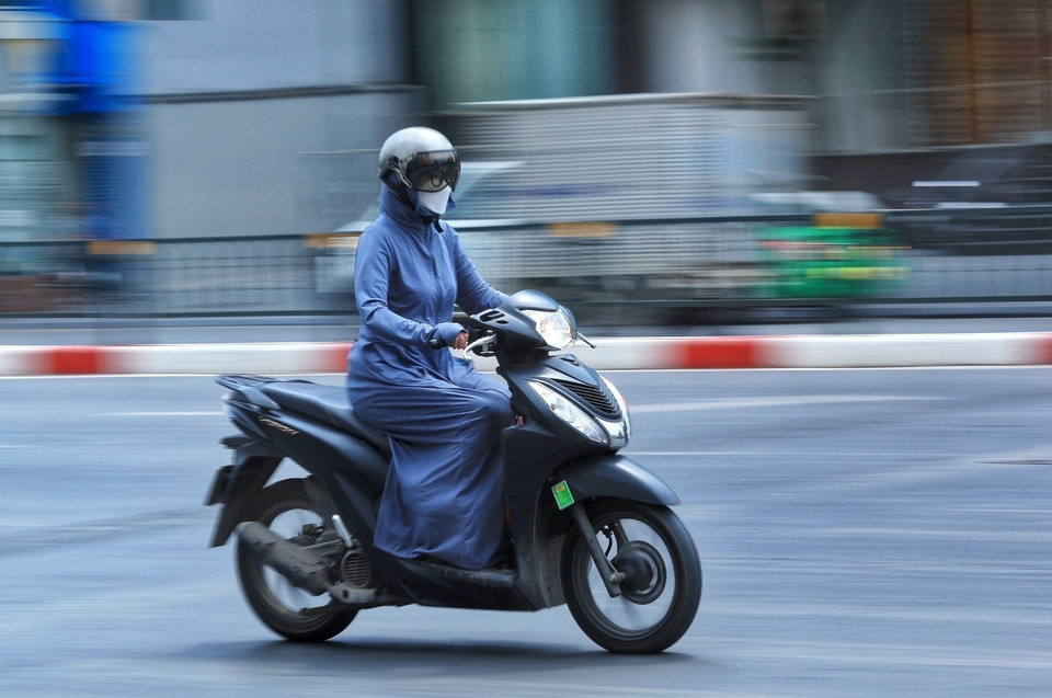 Người dân mặc đồ kín mít tránh nắng, nóng khi phải di chuyển trên đường ngày 28/6.(Ảnh: Hoàng Hiếu/TTXVN)