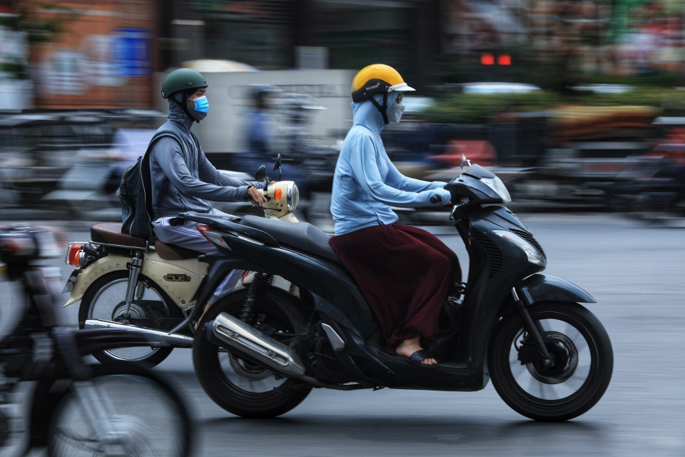 Người dân mặc đồ kín mít tránh nắng, nóng khi phải di chuyển trên đường ngày 28/6.(Ảnh: Hoàng Hiếu/TTXVN)