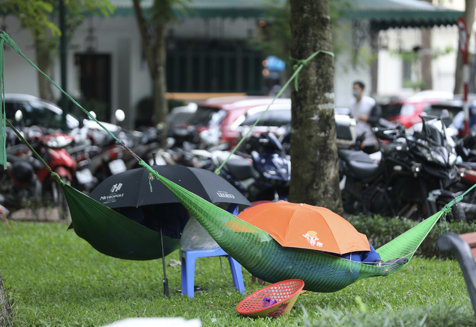 Nhiều người chọn nơi có bóng râm, mát để nghỉ trưa trong cái nóng oi bức ngày 28/6. (Ảnh: Hoàng Hiếu/TTXVN)