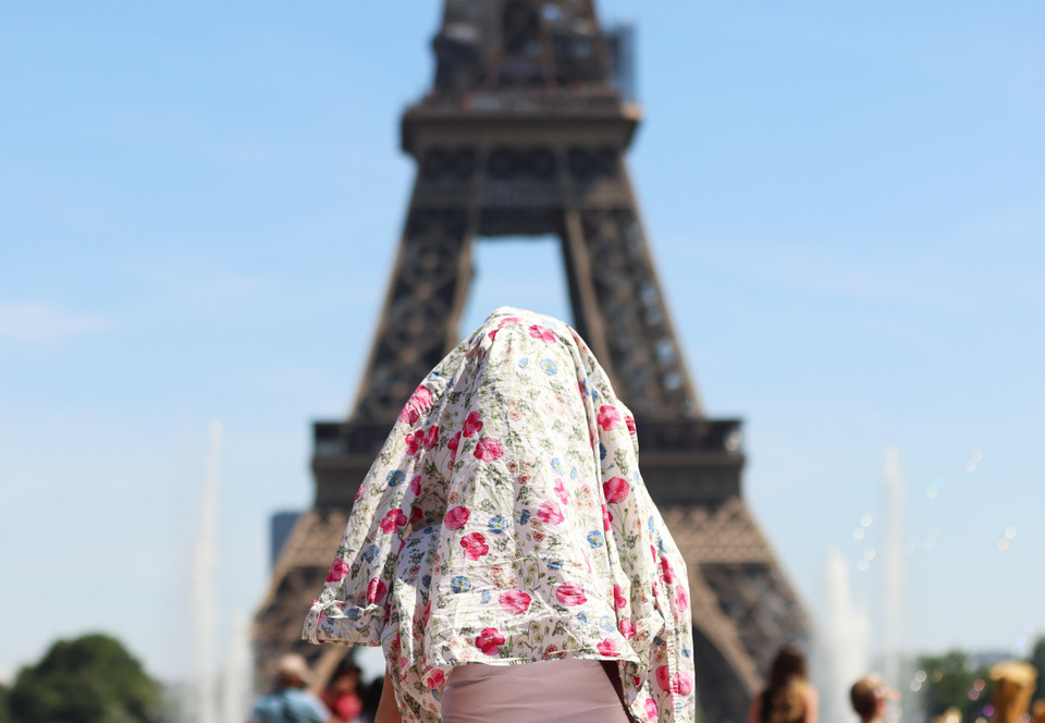 Người dân trùm kín đầu tránh nắng nóng tại Paris, Pháp, ngày 16/6/2022.(Ảnh: THX/TTXVN)