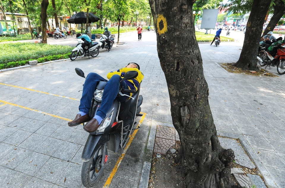 Phút nghỉ ngơi của lái xe công nghệ giữa trưa hè nóng bức. (Ảnh: Hoàng Hiếu/TTXVN)