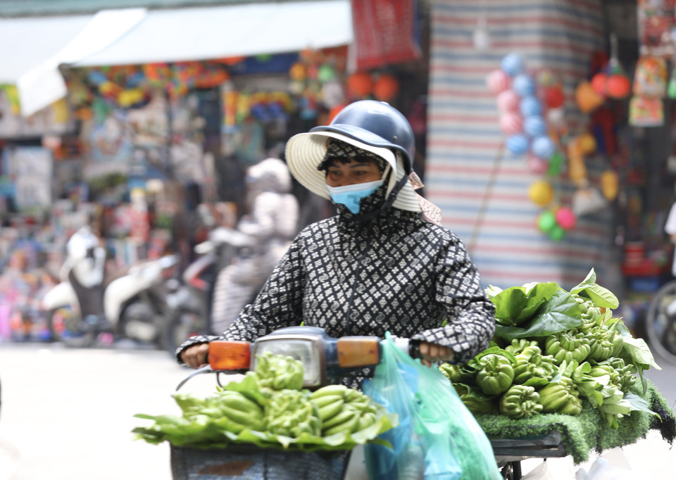  Một người bán hàng mệt mỏi trong thời tiết nắng nóng trưa 28/6/2022. (Ảnh: Hoàng Hiếu - TTXVN)