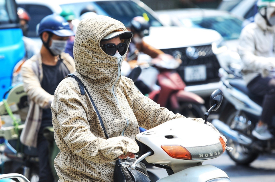 Người dân mặc đồ kín mít tránh nắng, nóng khi phải di chuyển trên đường ngày 28/6. (Ảnh: Hoàng Hiếu/TTXVN)