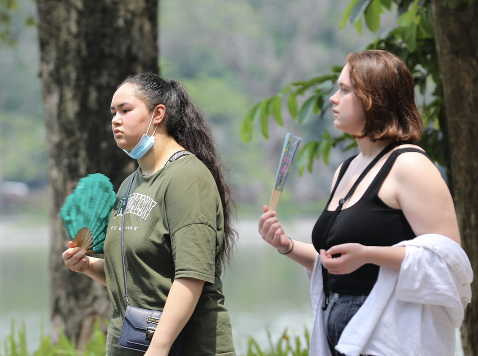 Hai khách nước ngoài di chuyển tại khu vực Hồ Gươm trong ngày nắng nóng 28/6. (Ảnh: Hoàng Hiếu/TTXVN)
