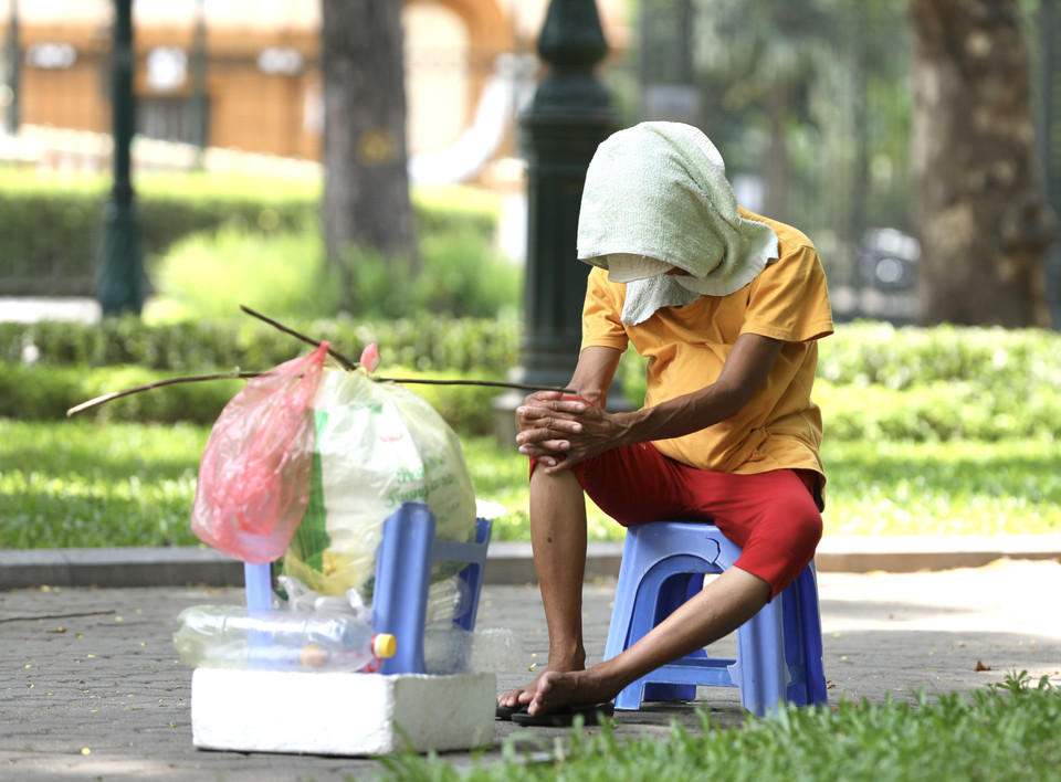 Một người bán hàng mệt mỏi trong thời tiết nắng nóng trưa 28/6/2022. (Ảnh: Hoàng Hiếu/TTXVN)