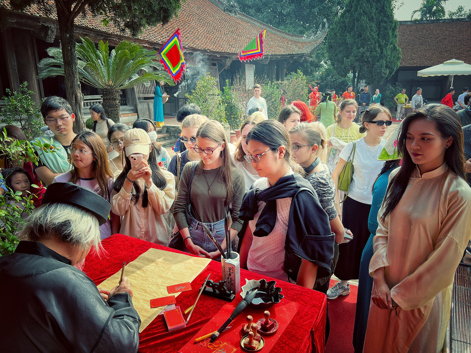 Du khách quốc tế xếp hàng xin chữ ông đồ, một trong những nét đẹp đầu Xuân của người Việt. (Ảnh: Mai Mai/Vietnam+)