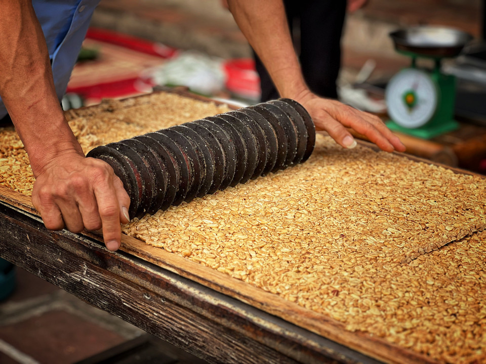 Các nghệ nhân của Đường Lâm trực tiếp biểu diễn làm kẹo lạc trong không gian lễ hội. (Ảnh: Mai Mai/Vietnam+)