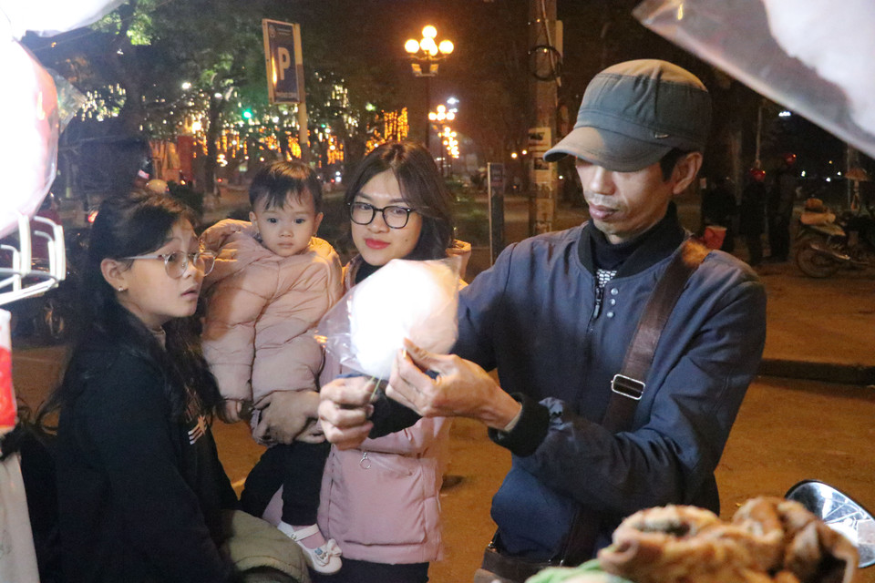 Anh Trương Phú Huyên, bán hàng kẹo kéo tại khu vực công viên Thống Nhất chia sẻ rằng kinh tế phục hồi sau đại dịch giúp việc buôn bán năm nay thuận lợi hơn. (Ảnh: Việt Anh/Vietnam+)