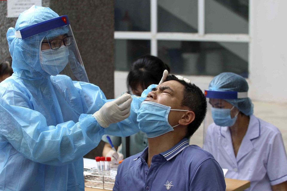 Nhân viên y tế lấy mẫu xét nghiệm COVID-19 cho người làm việc tại tòa nhà T&amp;T Group. (Ảnh: Tuấn Đức/TTXVN)