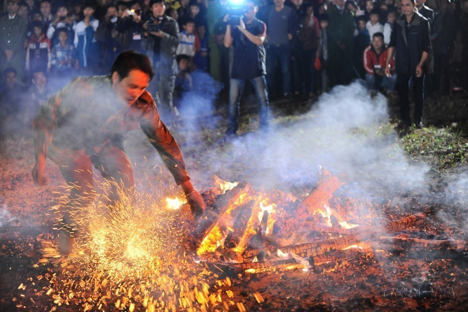 Sau khi được thầy cúng làm lễ, người thanh niên nhảy bật lên bằng cả hai chân và lao vào giữa đống lửa cháy rừng rực mà không bị bỏng (Hà Giang, 2013). (Ảnh: Nam Sương/TTXVN)