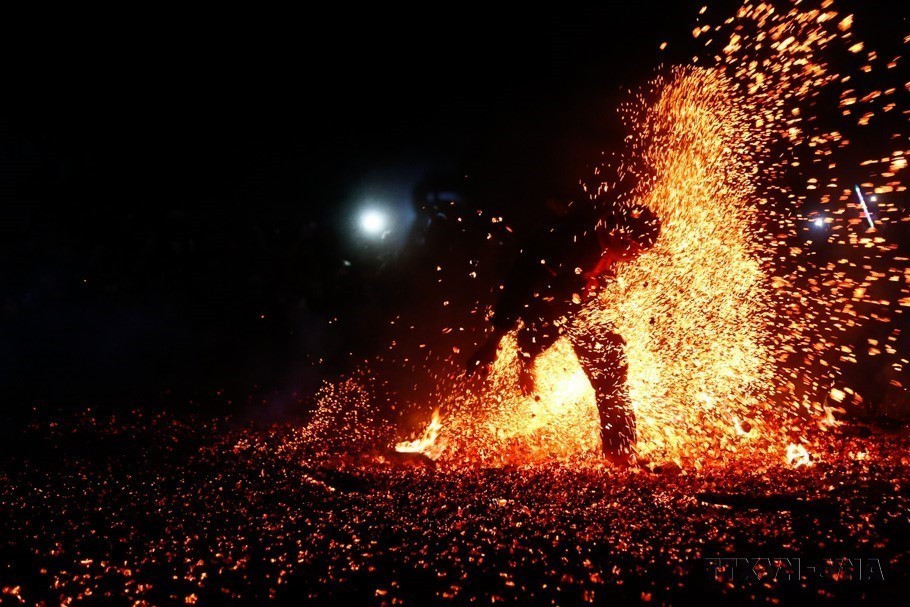 Sau khi được thầy cúng làm lễ, người thanh niên nhảy bật lên bằng cả hai chân và lao vào giữa đống lửa cháy rừng rực mà không bị bỏng (Tuyên Quang, 2023).(Ảnh: Nam Sương/TTXVN)