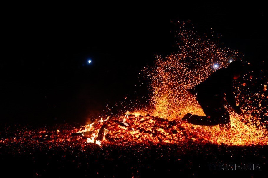 Sau khi được thầy cúng làm lễ, người thanh niên nhảy bật lên bằng cả hai chân và lao vào giữa đống lửa cháy rừng rực mà không bị bỏng (Tuyên Quang, 2023). (Ảnh: Nam Sương/TTXVN)