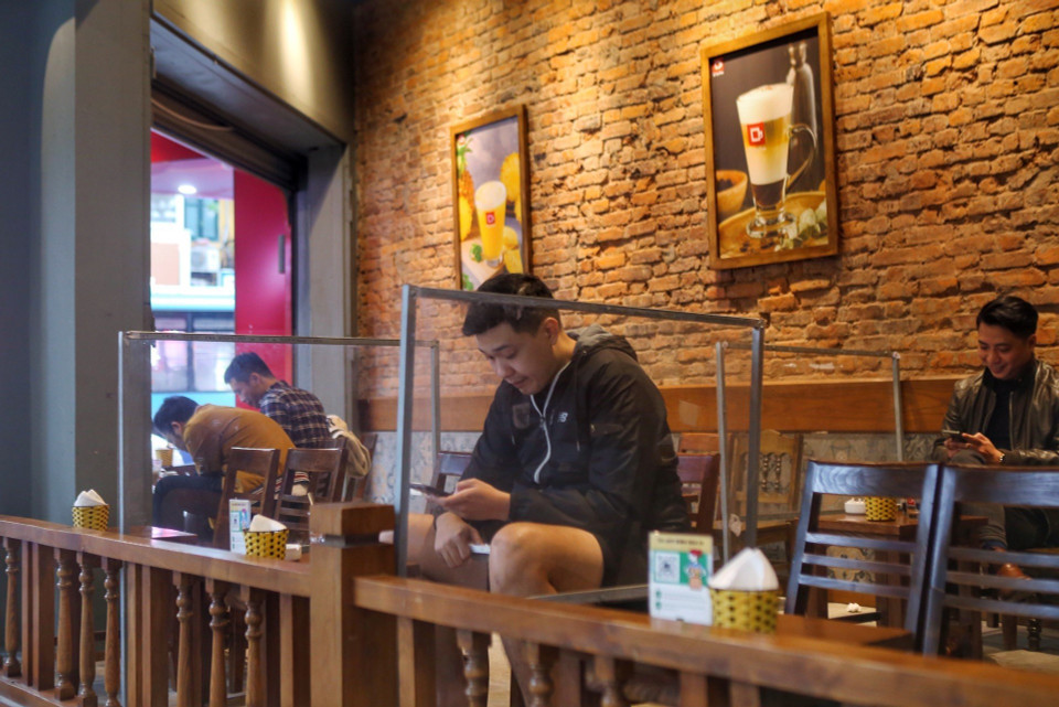 Các quán cà phê cũng được lắp vách ngăn và đảm bảo lượng khách theo đúng quy định của thành phố. (Ảnh: Tuấn Đức/TTXVN)