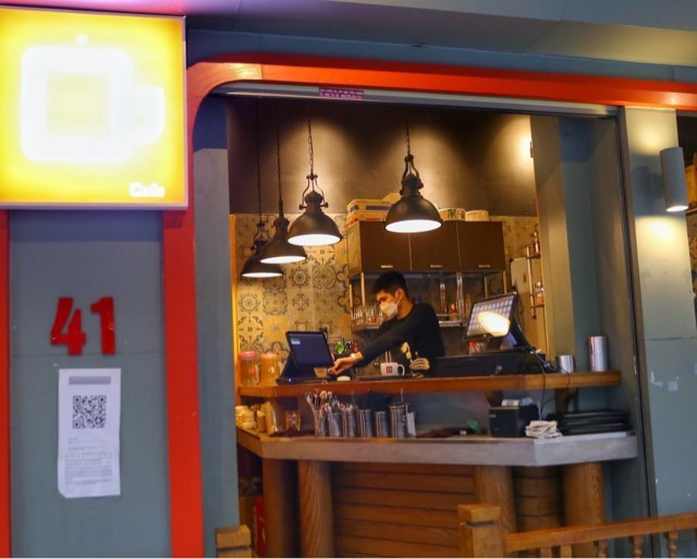 Để phòng chống dịch hiệu quả, các quán bán hàng đồ ăn uống đã trang bị tấm chắn giọt bắn và dán mã QR để khách khai báo y tế trực tuyến. (Ảnh: Tuấn Đức/TTXVN)