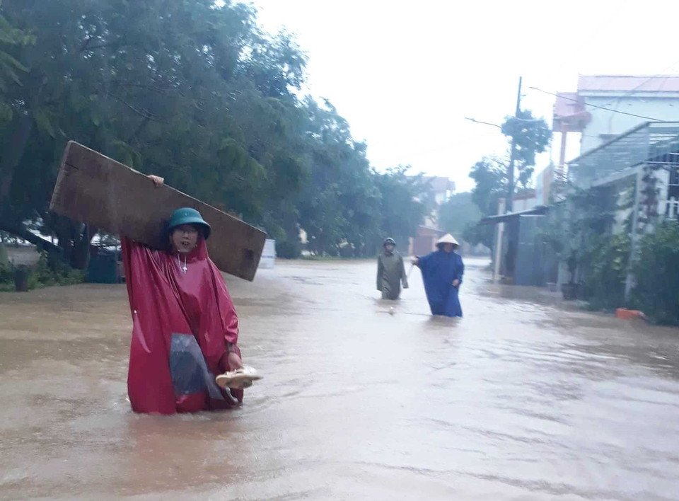 Người dân huyện Lệ Thủy, Quảng Bình lội nước di chuyển do mưa to gây ngập lụt. (Ảnh: TTXVN phát)