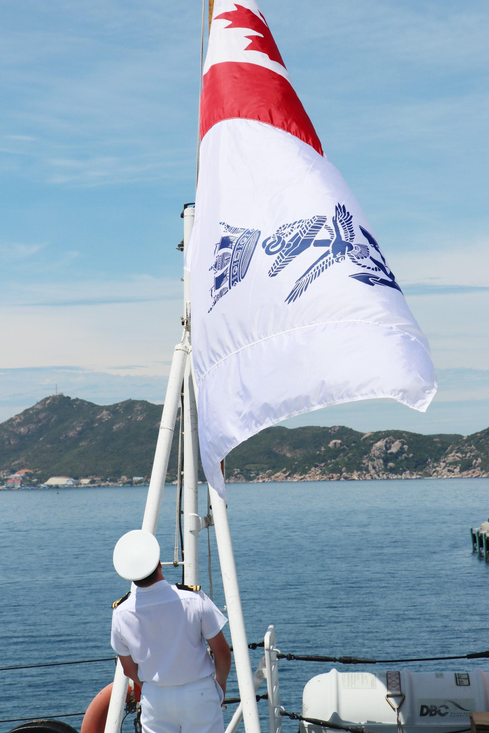 Một sỹ quan tàu Regina đứng dưới lá cờ Hải quân Hoàng gia Canada, phía trước là biển vịnh Cam Ranh. (Ảnh: Tiên Minh/TTXVN)