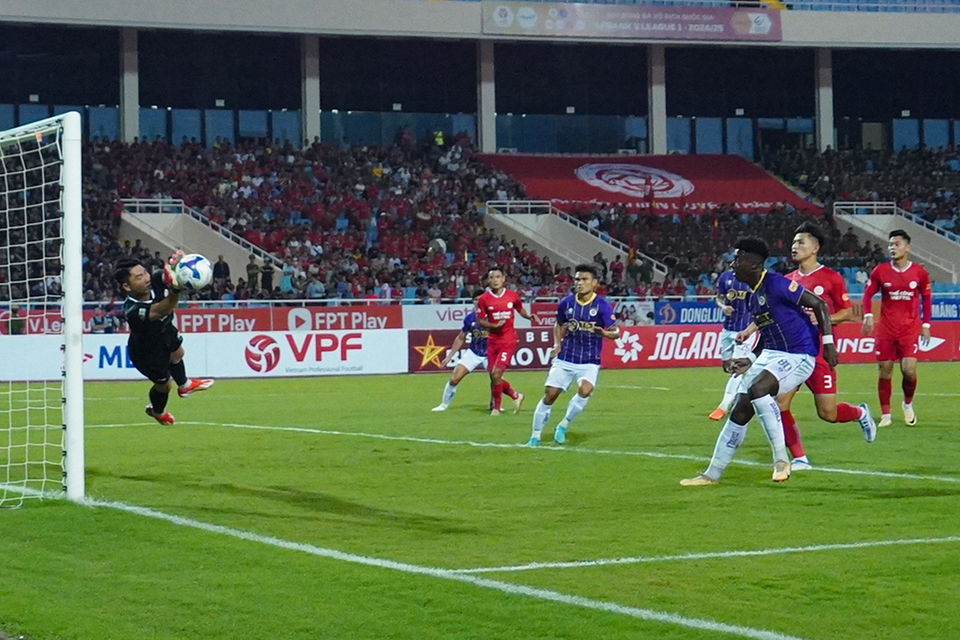 Thủ môn Phạm Văn Phong (áo đen) vất vả cản phá pha sút phạt của đội trưởng Văn Quyết bên phía Hà Nội FC. (Ảnh: Việt Anh/Vietnam+)