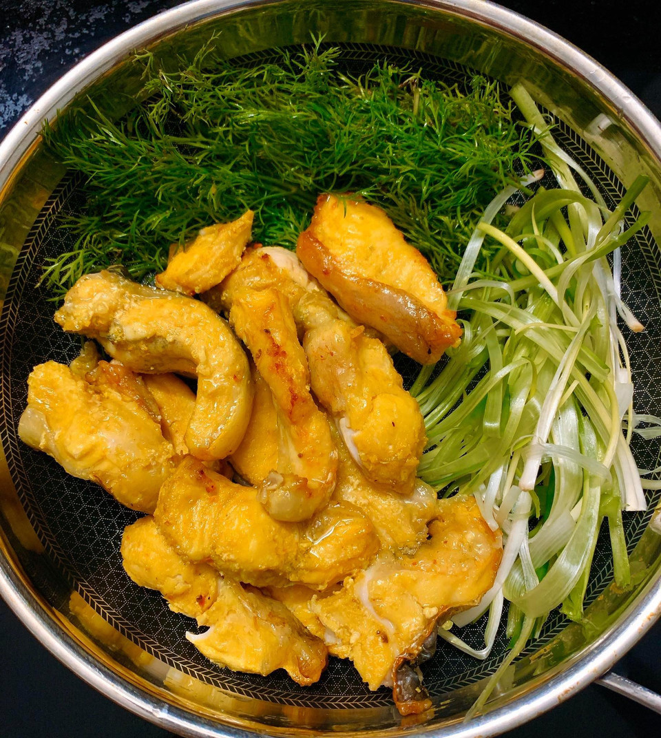 Cá lấy từ nồi chiên để nguội cho cứng miếng cá. (Ảnh: Vietnam+)