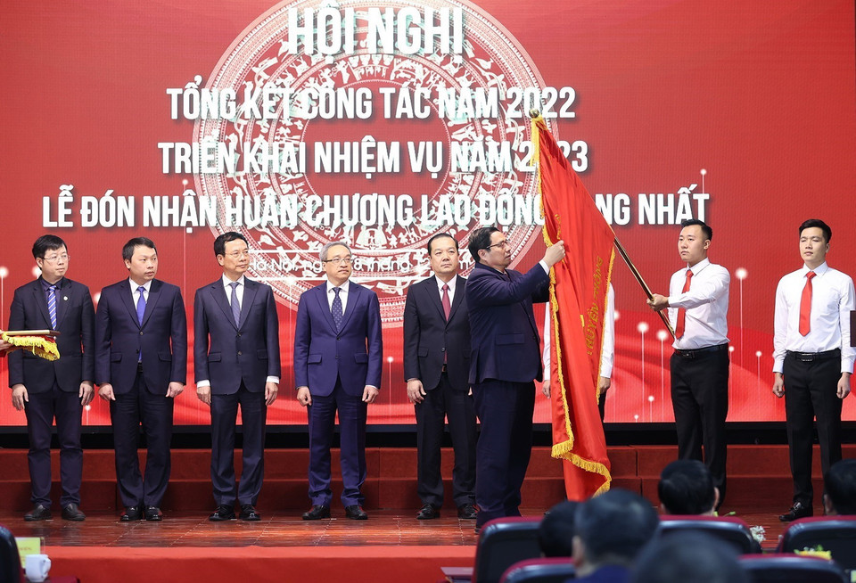 Thủ tướng Phạm Minh Chính gắn Huân chương Lao động hạng Nhất lên Cờ truyền thống của Bộ Thông tin và Truyền thông. (Ảnh: Dương Giang/TTXVN)