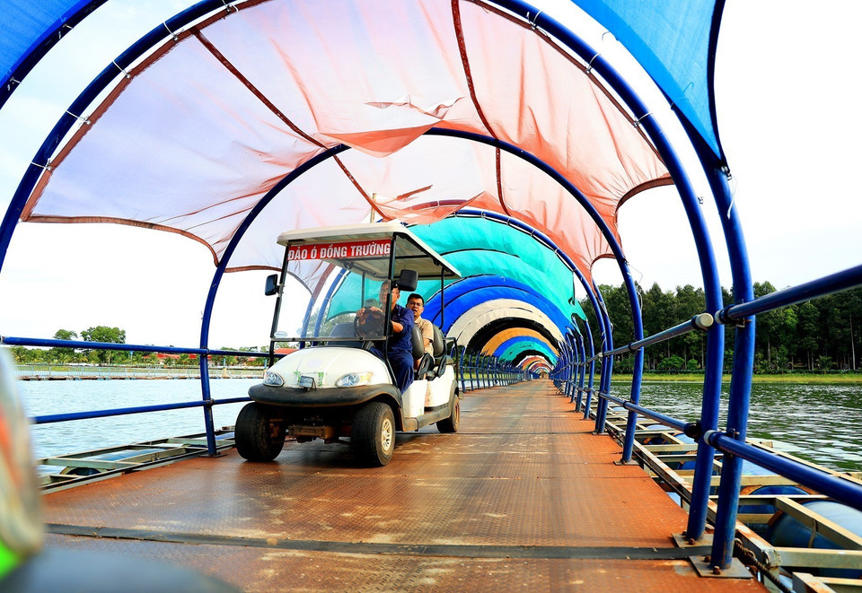 Du khách đi xe điện qua cầu phao nối hai hòn đảo. (Ảnh: Hồng Đạt /TTXVN)