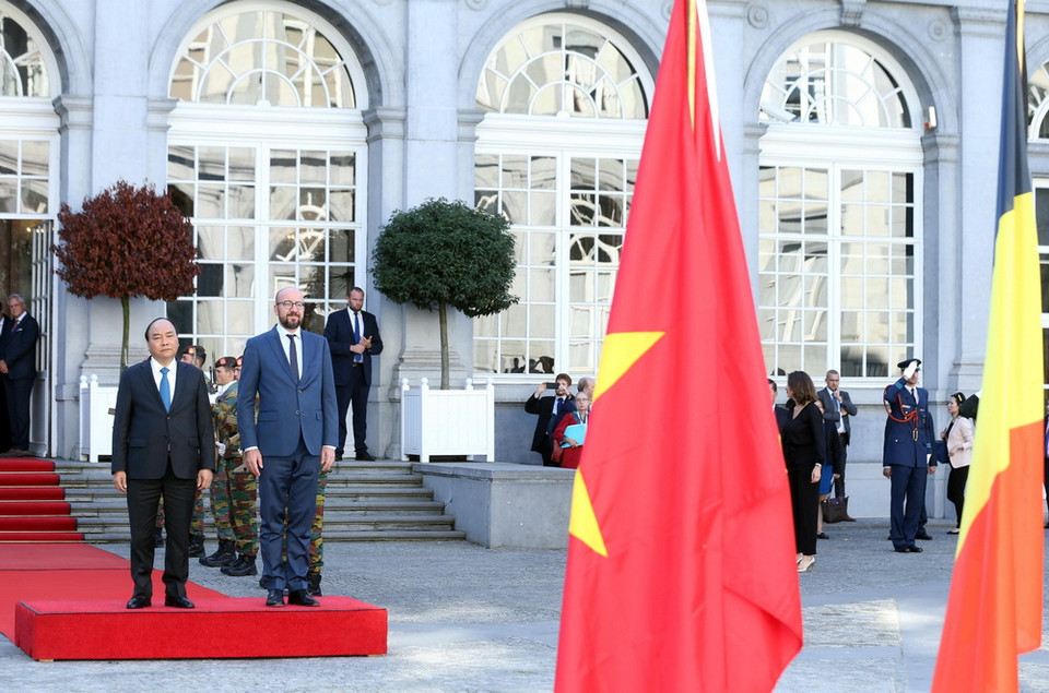 Thủ tướng Vương quốc Bỉ Charles Michel và Thủ tướng Nguyễn Xuân Phúc trên bục danh dự, nghe quân nhạc cử Quốc thiều hai nước, tại lễ đón. (Ảnh: Thống Nhất/TTXVN)