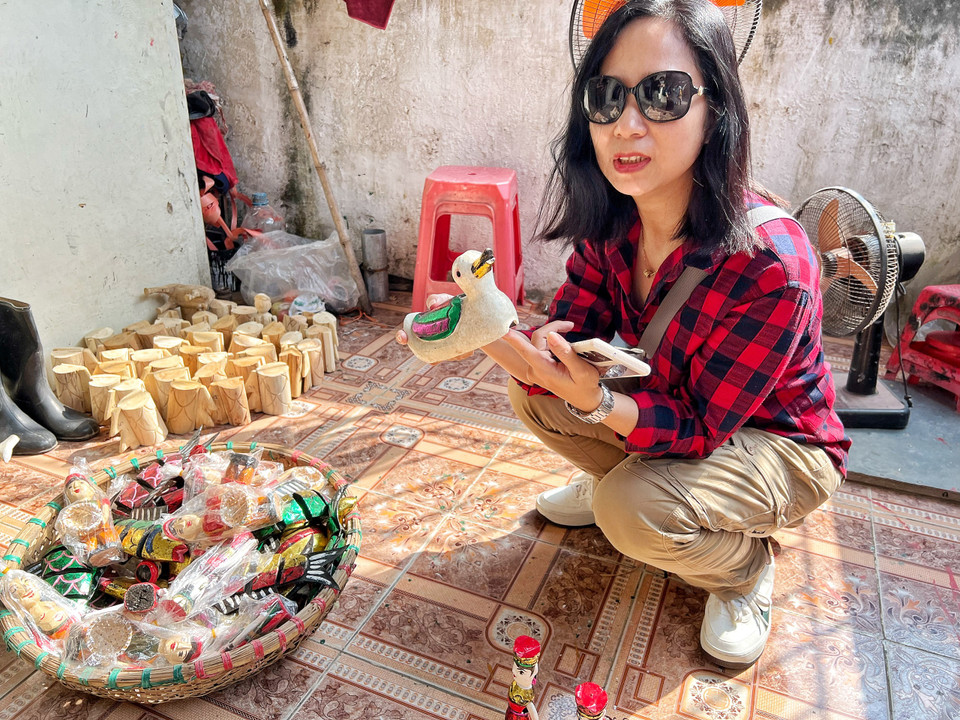 Du khách từ Hà Nội thích thú chọn mua những con rối lưu niệm của làng nghề. (Ảnh: Mai Mai/Vietnam+)