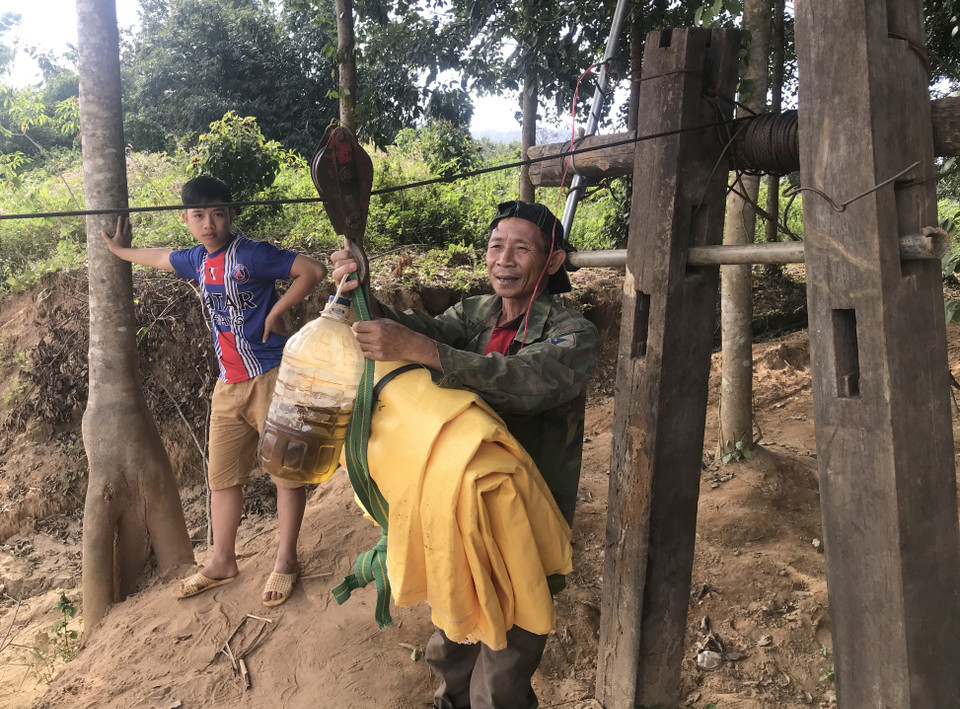 Người dân liều mình đu dây qua sông Pô Kô để mua lương thực. (Ảnh: Khoa Chương/TTXVN)