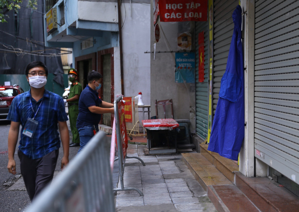 Lực lượng chức năng phường Đồng Nhân tiến hành lập rào chắn phong tỏa tạm thời từ số 34 đến 42 phố Hương Viên. (Ảnh: Hoàng Hiếu/TTXVN)