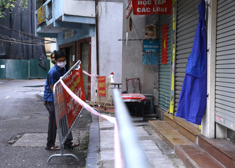 Lực lượng chức năng phường Đồng Nhân tiến hành lập rào chắn phong tỏa tạm thời từ số 34 đến 42 phố Hương Viên. (Ảnh: Hoàng Hiếu/TTXVN)